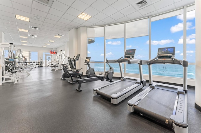 workout area with a paneled ceiling and a water view