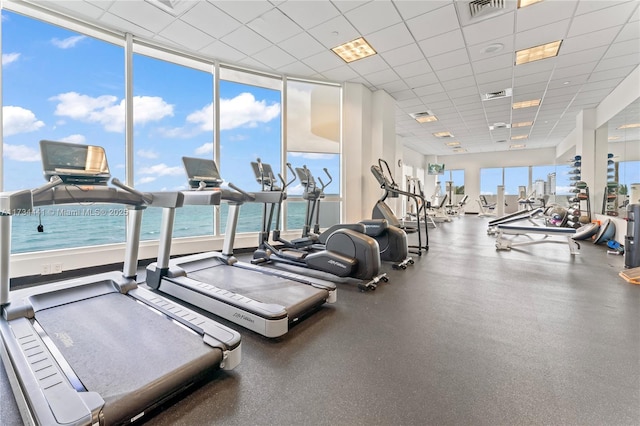 workout area featuring a paneled ceiling and a water view