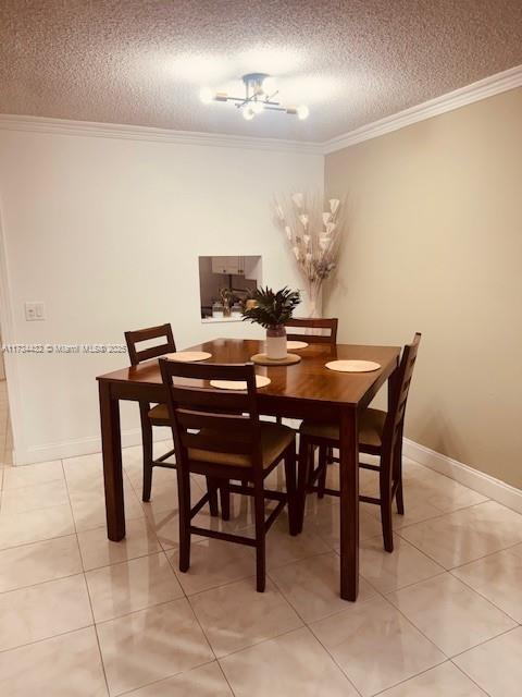 dining area featuring crown molding, a textured ceiling, baseboards, and light tile patterned floors