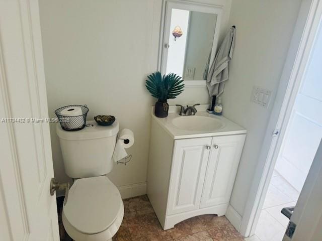 bathroom with toilet, vanity, and baseboards