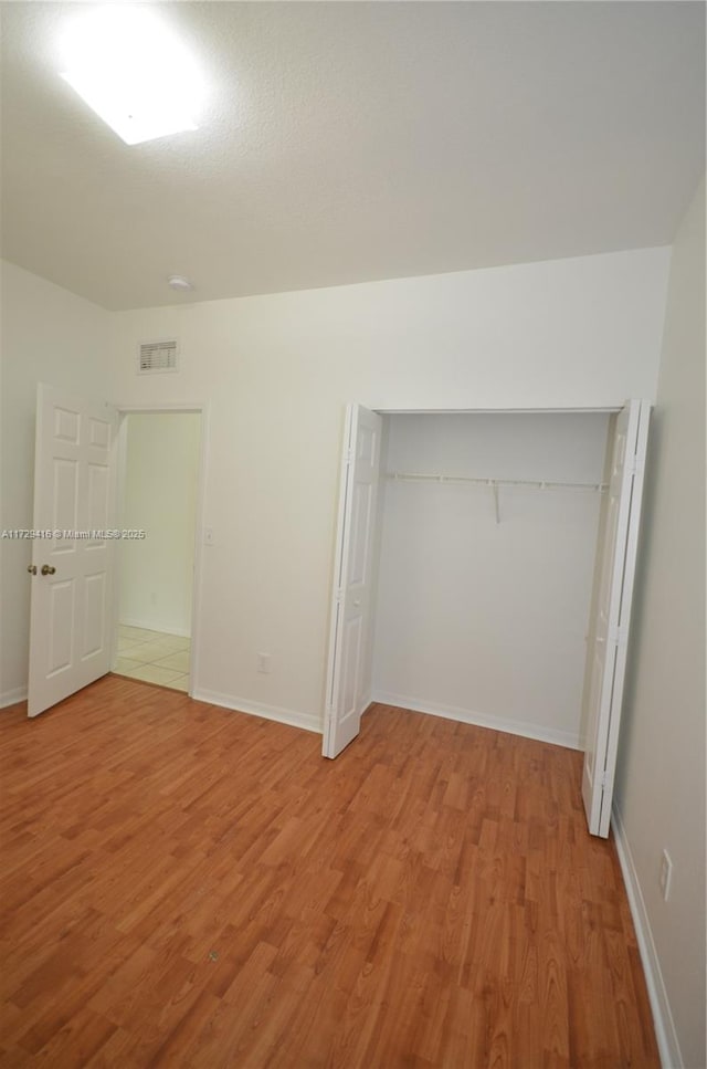 unfurnished bedroom with a closet and light wood-type flooring