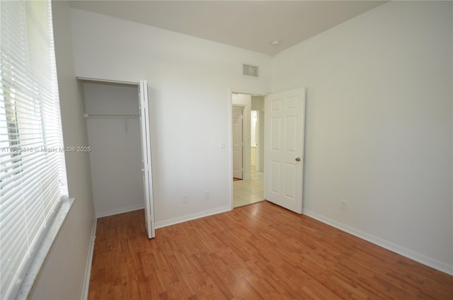 unfurnished bedroom featuring a spacious closet, light hardwood / wood-style flooring, and a closet