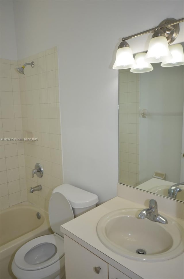 full bathroom featuring tiled shower / bath, vanity, and toilet