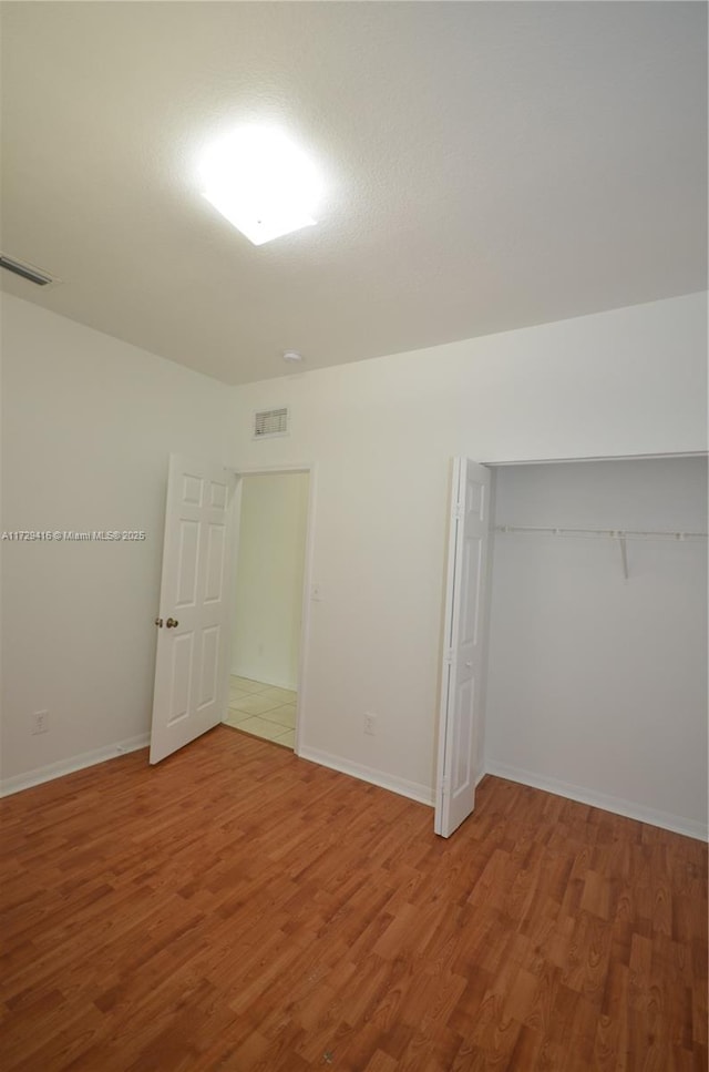 unfurnished bedroom featuring hardwood / wood-style floors and a closet