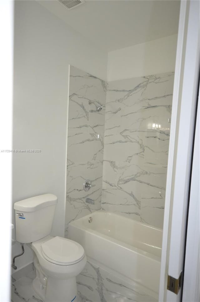 bathroom featuring tiled shower / bath combo and toilet