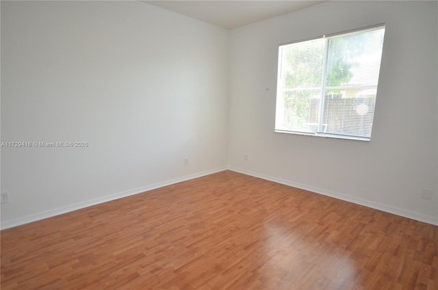 spare room featuring wood-type flooring and plenty of natural light