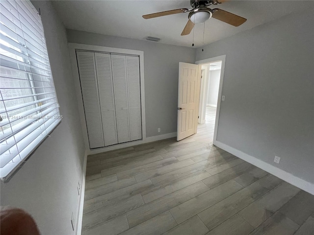 unfurnished bedroom featuring ceiling fan, a closet, and light wood-type flooring