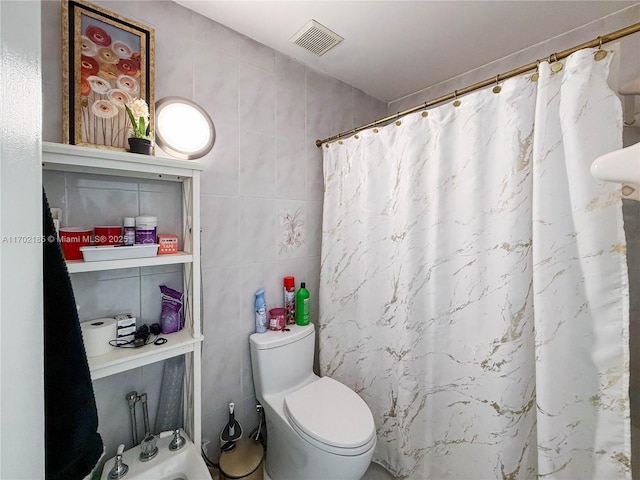 bathroom featuring toilet, curtained shower, and tile walls