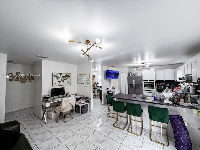 kitchen featuring white cabinets, a breakfast bar area, stainless steel fridge, and kitchen peninsula