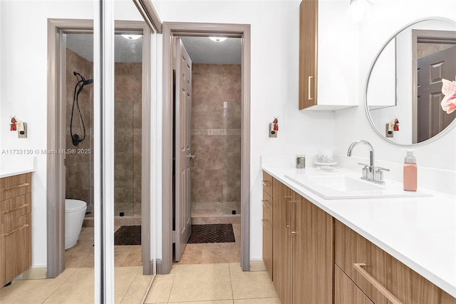 bathroom with tiled shower, vanity, toilet, and tile patterned flooring