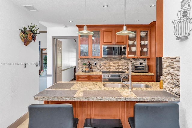 kitchen featuring a breakfast bar area, decorative light fixtures, kitchen peninsula, stainless steel appliances, and decorative backsplash