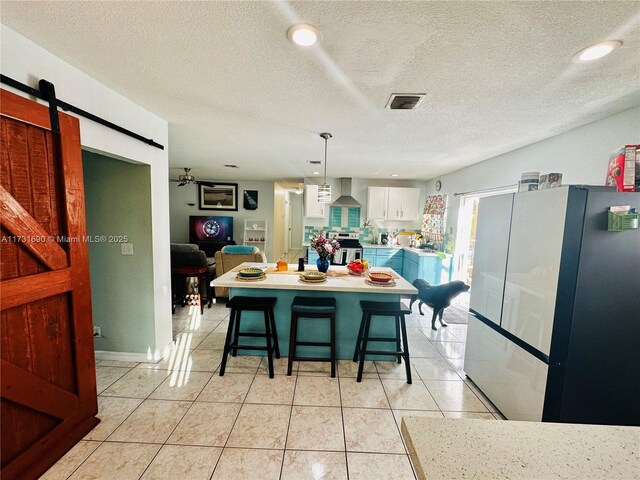 kitchen featuring a center island, a breakfast bar area, white cabinets, and wall chimney exhaust hood