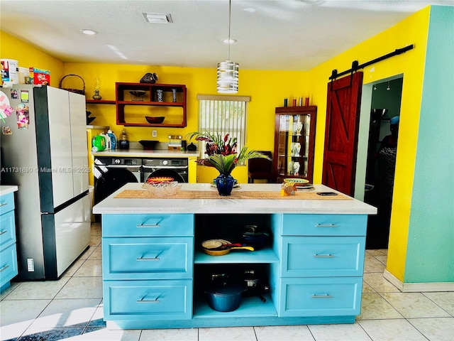 kitchen with a center island, hanging light fixtures, light tile patterned floors, stainless steel refrigerator, and a barn door