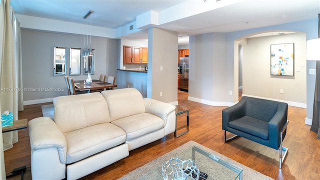 living room featuring baseboards, arched walkways, and wood finished floors