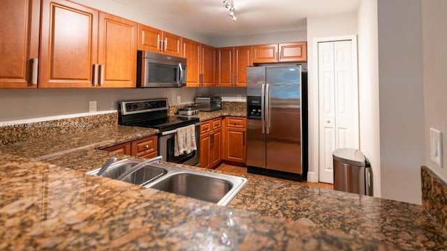 kitchen featuring a sink, stainless steel appliances, brown cabinets, and rail lighting