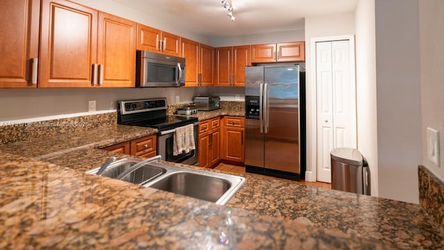 kitchen with appliances with stainless steel finishes, sink, and dark stone counters