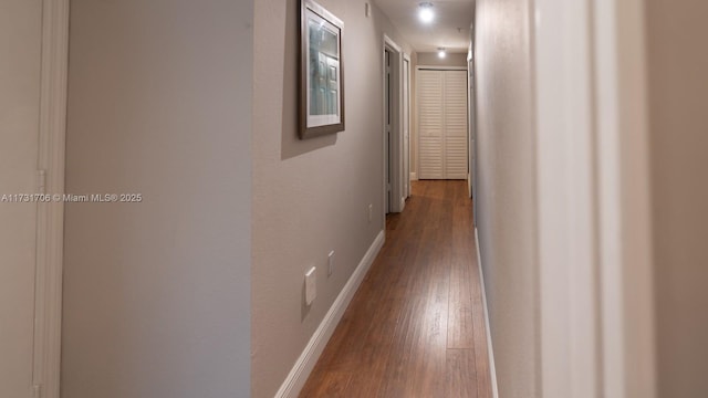 hallway with dark wood finished floors and baseboards