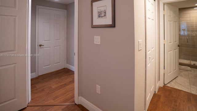 corridor featuring wood finished floors and baseboards