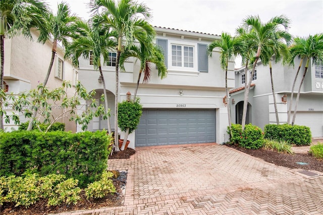 view of front of home featuring decorative driveway, an attached garage, and stucco siding