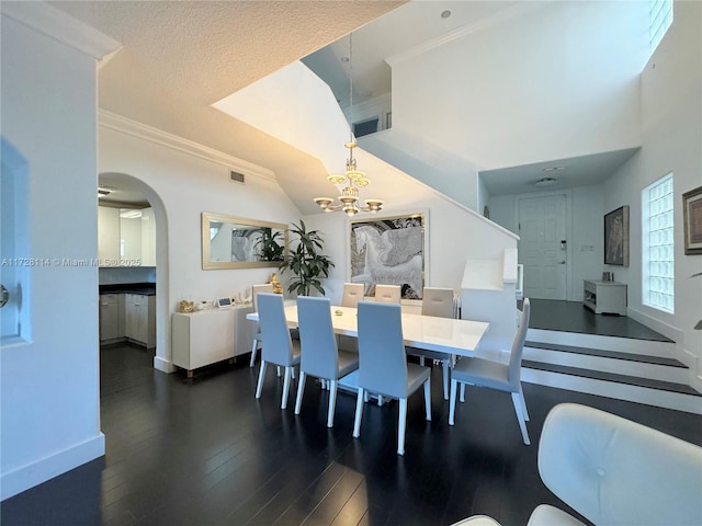 dining room featuring baseboards, visible vents, dark wood finished floors, arched walkways, and an inviting chandelier