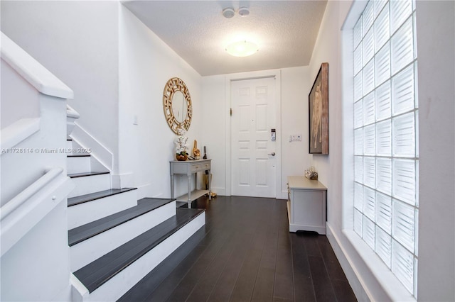 foyer featuring stairs, a textured ceiling, and dark wood-style floors