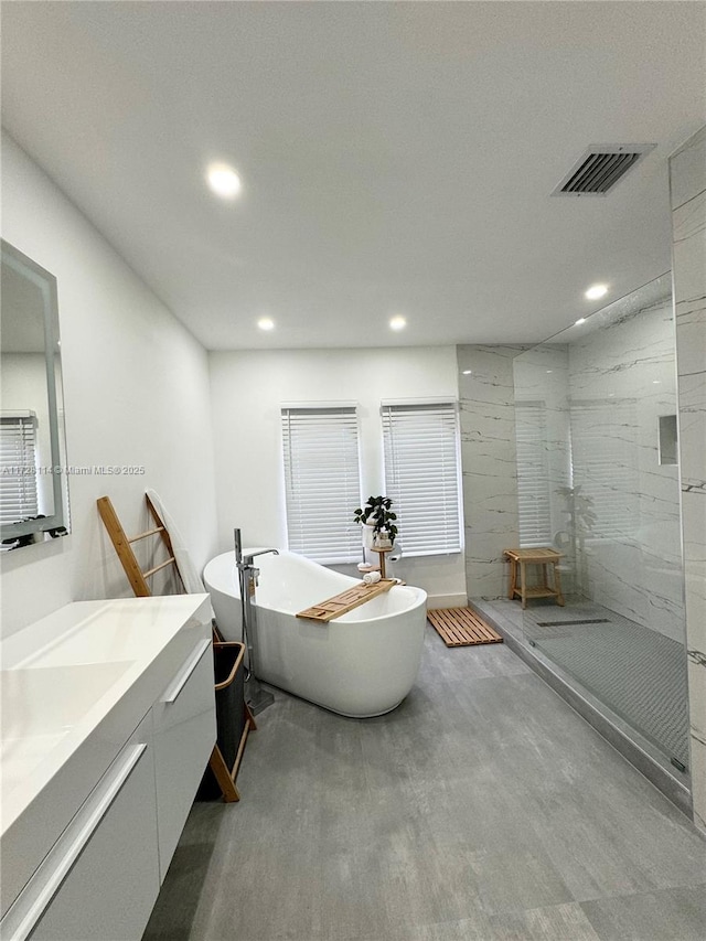 bathroom featuring a marble finish shower, visible vents, vanity, a freestanding tub, and recessed lighting