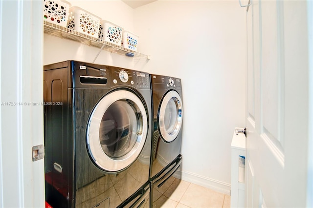 clothes washing area with laundry area, washing machine and dryer, baseboards, and light tile patterned flooring