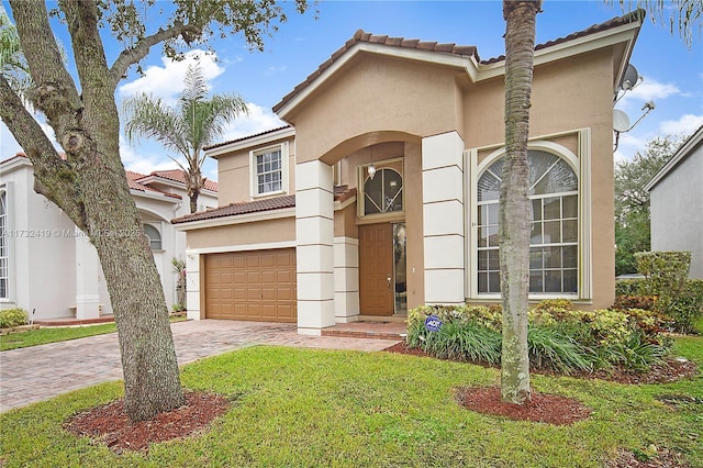 mediterranean / spanish home featuring a garage and a front yard