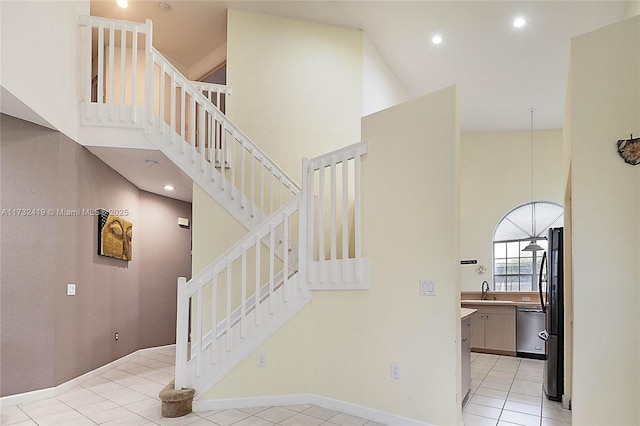 stairway with a high ceiling, sink, and tile patterned flooring