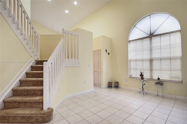 stairway featuring tile patterned floors and high vaulted ceiling