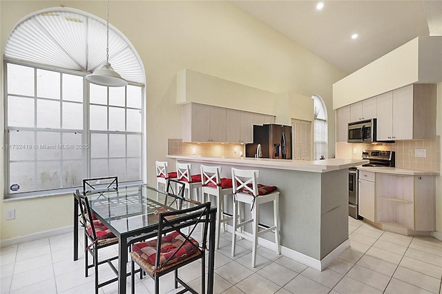 kitchen featuring appliances with stainless steel finishes, decorative light fixtures, high vaulted ceiling, and backsplash