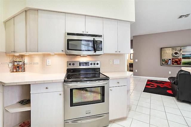 kitchen featuring light tile patterned floors, decorative backsplash, and stainless steel appliances