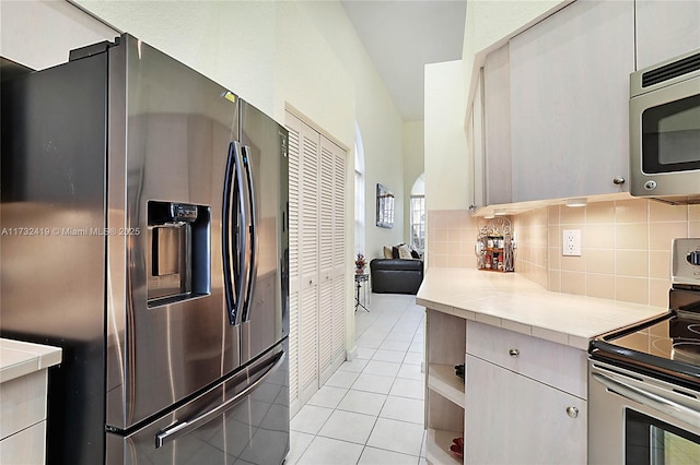 kitchen with backsplash, tile counters, light tile patterned flooring, and appliances with stainless steel finishes