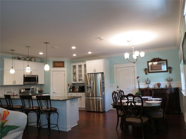 kitchen with stainless steel appliances, pendant lighting, white cabinets, and a kitchen breakfast bar