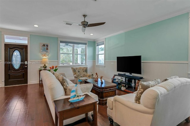 living room featuring ceiling fan, visible vents, ornamental molding, wainscoting, and hardwood / wood-style floors