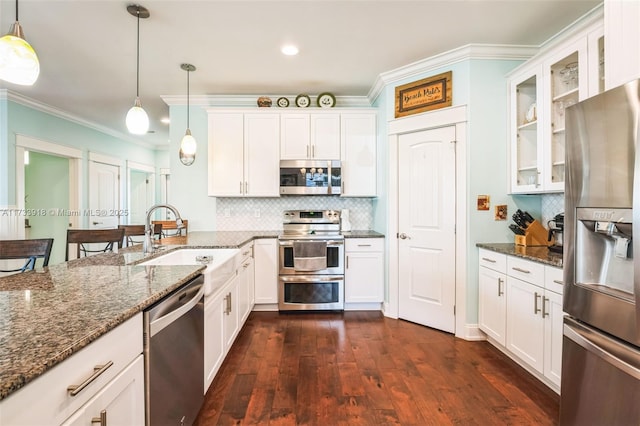 kitchen featuring stainless steel appliances, glass insert cabinets, white cabinetry, a sink, and dark stone counters