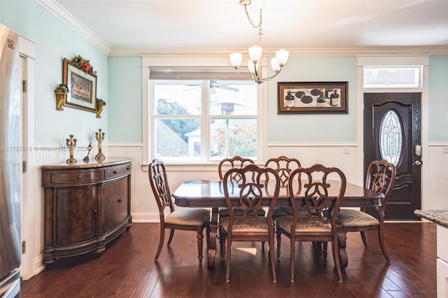 dining space featuring a wainscoted wall, a notable chandelier, dark wood finished floors, and crown molding