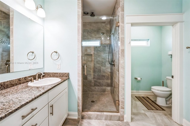 full bathroom featuring baseboards, toilet, a shower stall, and vanity