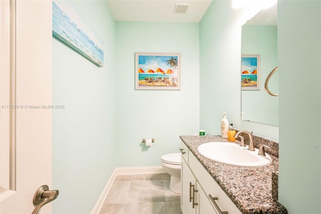 bathroom with toilet, vanity, visible vents, and baseboards