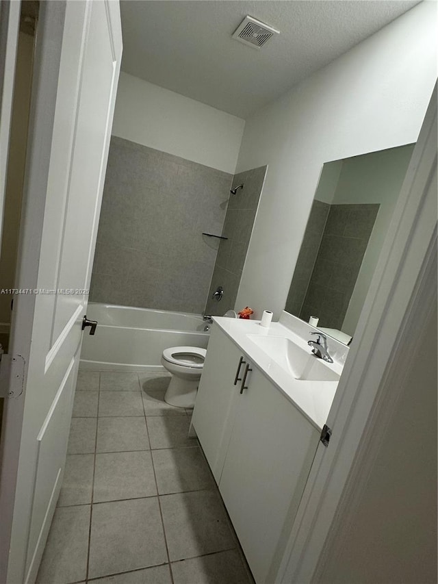 full bathroom with tile patterned floors, toilet, tiled shower / bath, a textured ceiling, and vanity