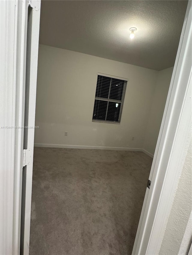 carpeted empty room featuring a textured ceiling