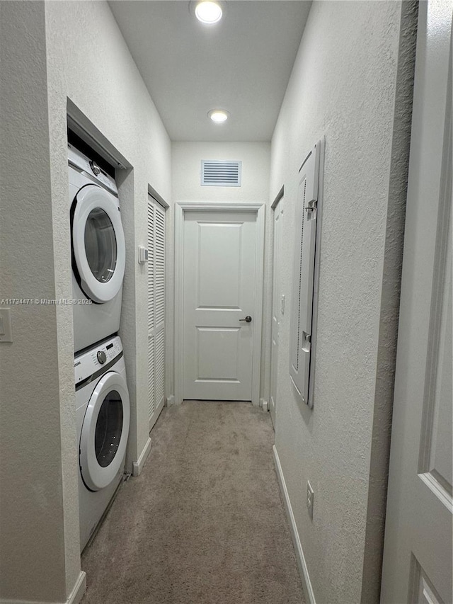 washroom featuring light colored carpet and stacked washer / dryer