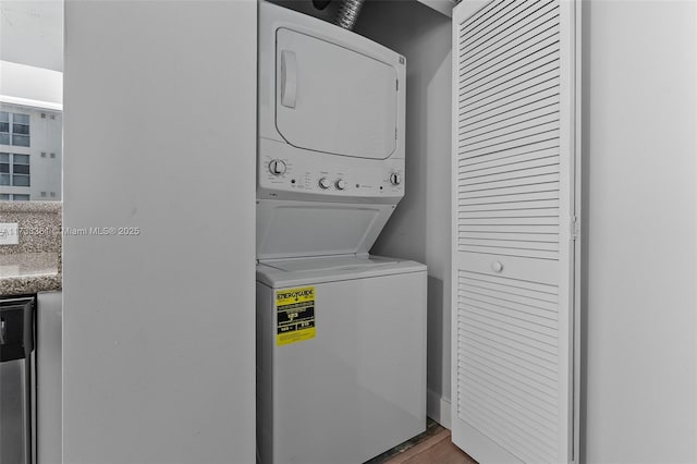 clothes washing area featuring stacked washing maching and dryer and hardwood / wood-style floors