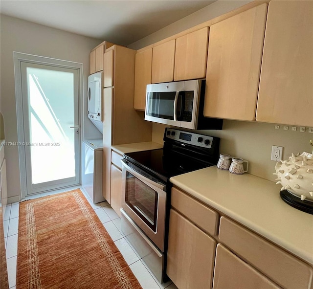 kitchen with light tile patterned floors, stacked washing maching and dryer, plenty of natural light, stainless steel appliances, and light brown cabinetry