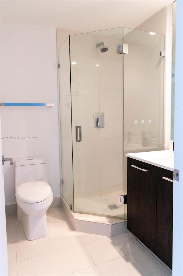 bathroom featuring tile patterned flooring, vanity, a shower with shower door, and toilet