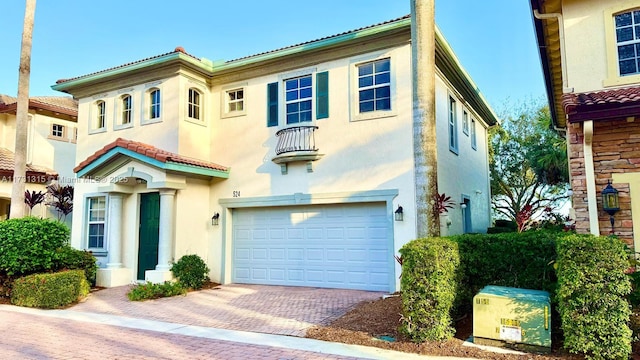 mediterranean / spanish home featuring a garage, decorative driveway, a tile roof, and stucco siding