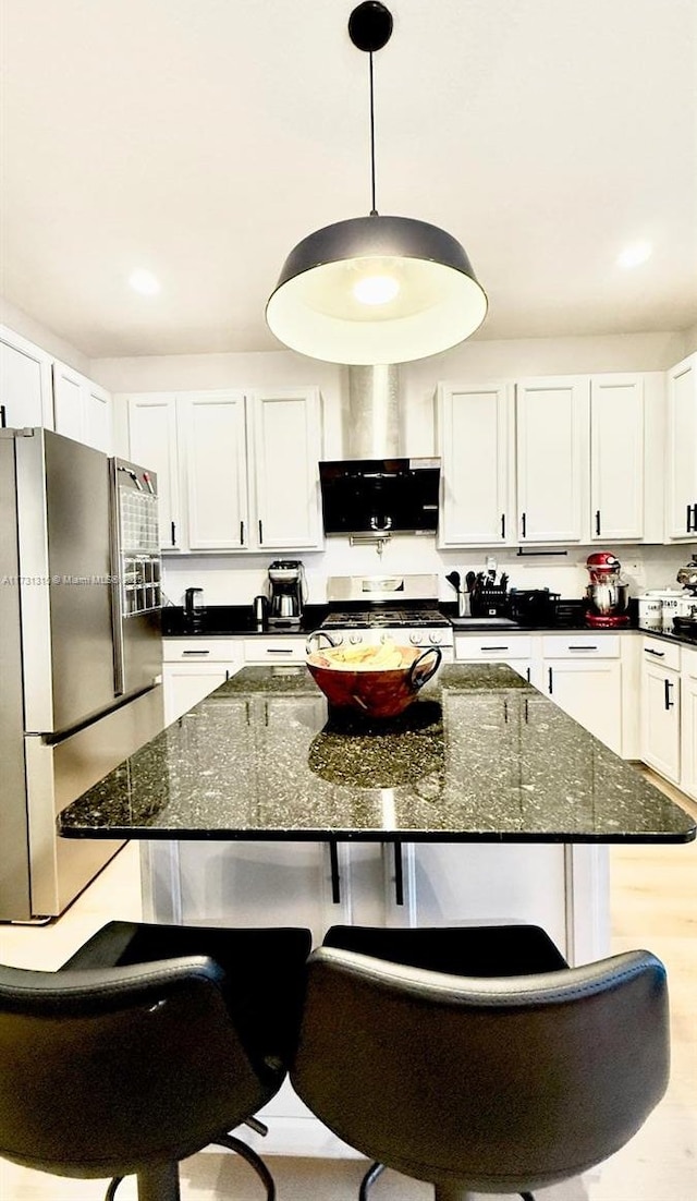 kitchen with stainless steel appliances, exhaust hood, a kitchen bar, and white cabinets