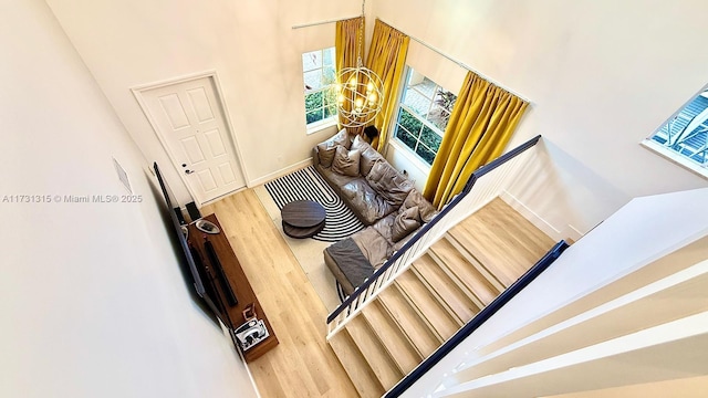 stairway featuring a notable chandelier, baseboards, and wood finished floors