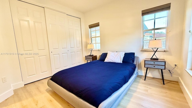 bedroom featuring a closet, baseboards, and light wood finished floors