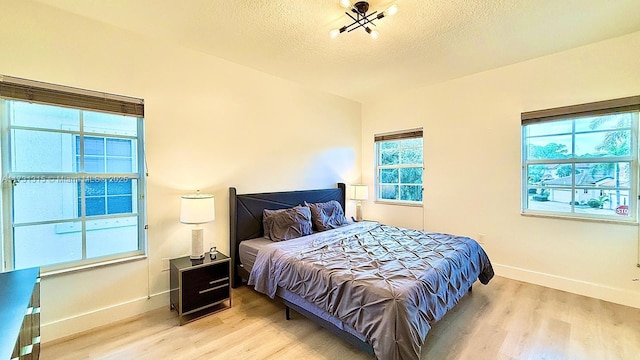 bedroom with baseboards, light wood-style flooring, and a textured ceiling